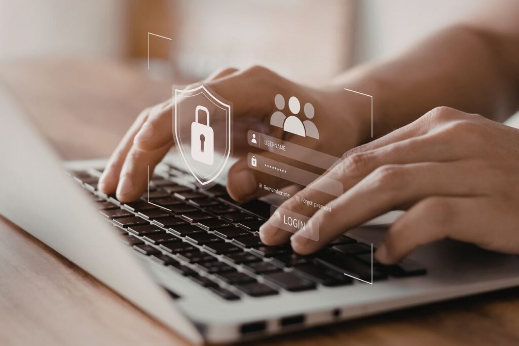 Zbliżenie na dłonie piszące na laptopie z widocznymi ikonami zabezpieczeń danych