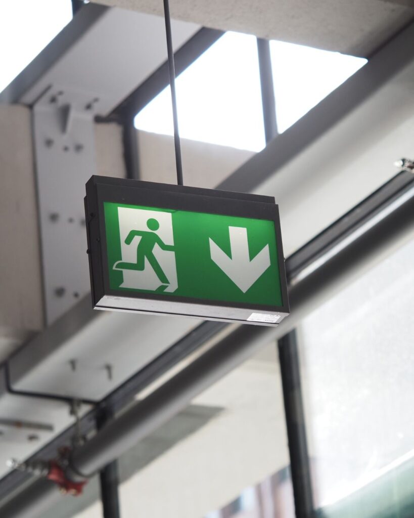 Znak wyjścia ewakuacyjnego z kierunkiem ewakuacji w budynku