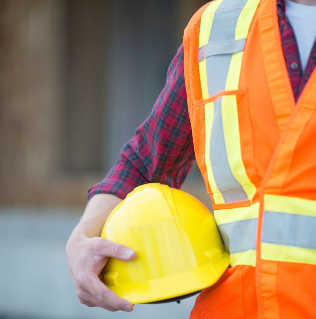 Pracownik w kamizelce odblaskowej trzymający kask ochronny